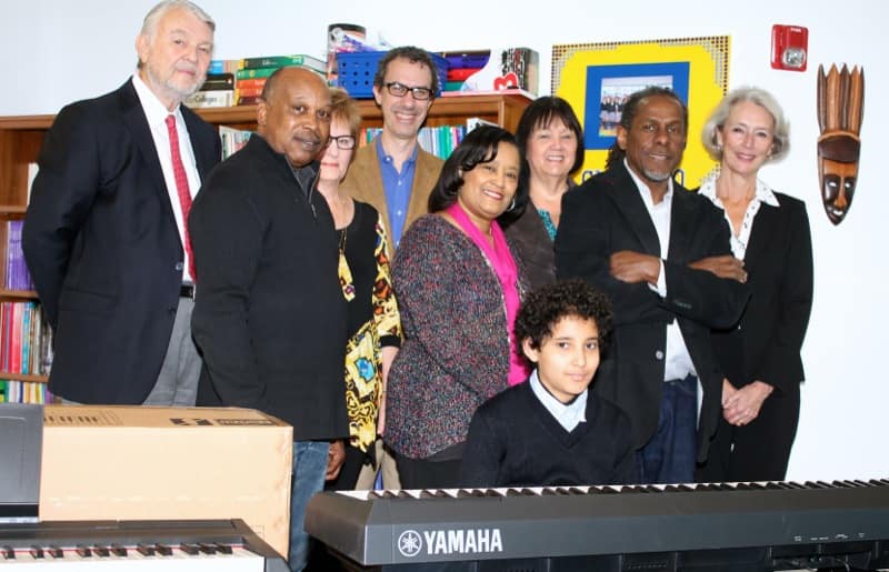 (L-R): Ken Albrecht, founder of the Carter Albrecht Music Foundation, Johnny Harris, store manager Metroplex Piano Dallas, Judy Albrecht, Founder CAMF, Salah Boukadoum, board member CAMF and Founder and CEO of Good Returns, Karen Harkey, Director at Choice Leadersihp Academy, Janis Evans, Trumpets4Kids board member, Freddie Jones, Founder and Artistic Director of Trumpets4Kids, Lynn Nikaidoh, supporter of CAMF. At the keyboard: Maphios Mekbeb-Gillette, student at Choice Leadership Academy. 